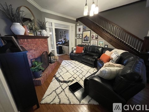 A living room with a black leather couch and a fireplace.