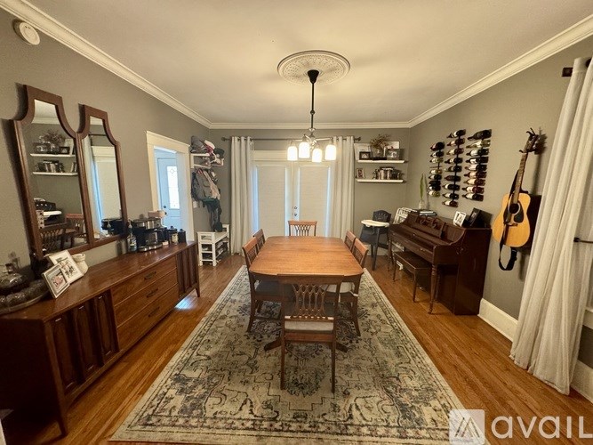 A living room with a wooden floor and a rug in the center.