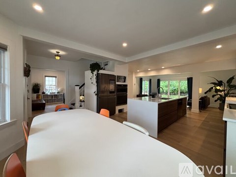 A modern living room with a white dining table and orange chairs.
