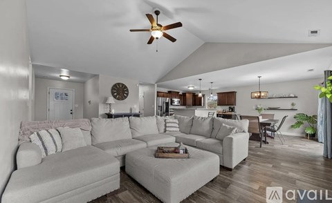 A living room with a large couch and a ceiling fan.