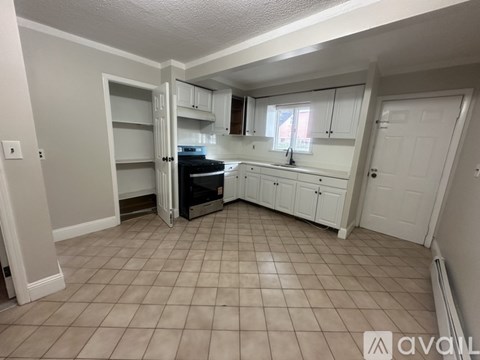 A kitchen with white cabinets and a tiled floor.