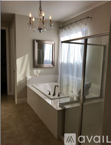 A bathroom with a chandelier, a bathtub, and a mirror.