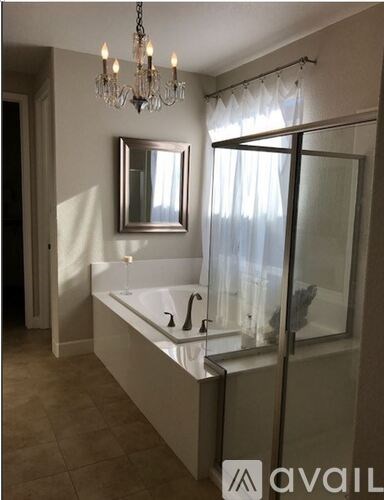 A bathroom with a chandelier, a bathtub, and a mirror.