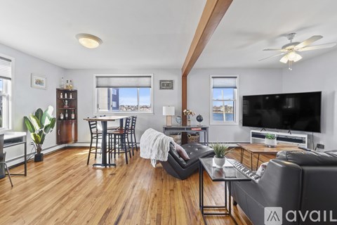 A living room with a black leather couch and a wooden floor.