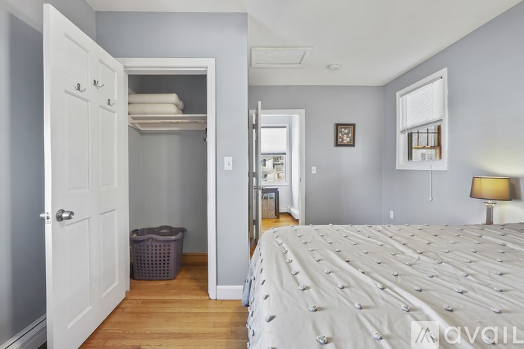 A bedroom with a large bed and a closet with a laundry basket inside.