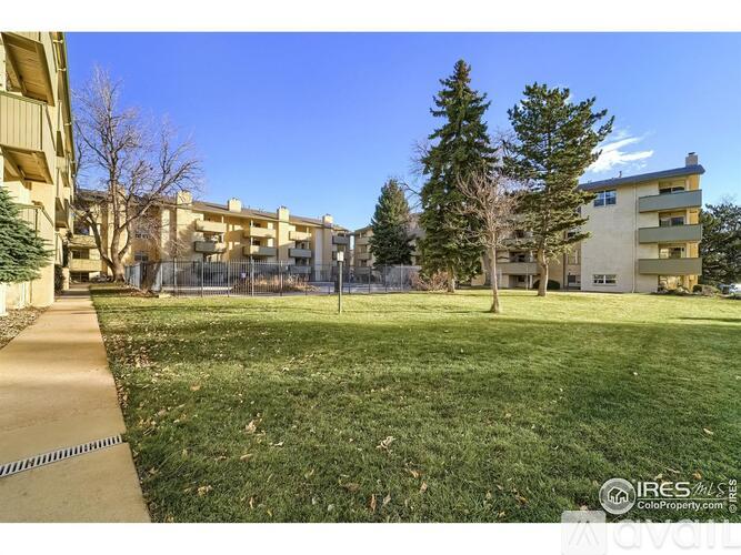 A grassy area in front of apartment buildings with a clear blue sky.