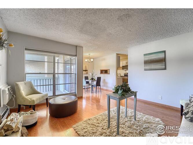 A living room with a brown ottoman and a glass table with a plant on it.