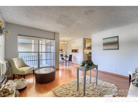 A living room with a brown ottoman and a glass table with a plant on it.