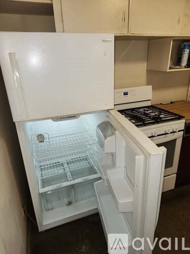 A white fridge with the door open and a stove in the background.