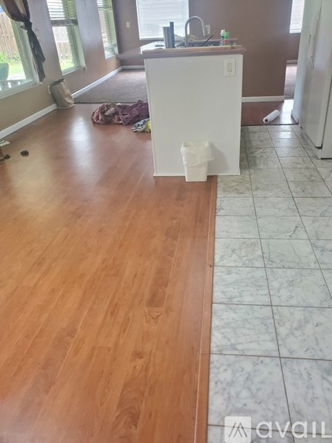 A kitchen with a white fridge and wooden floors.