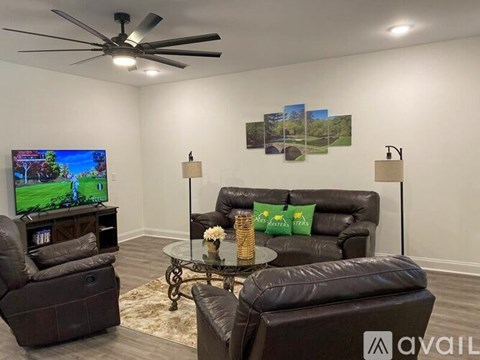 A living room with a brown leather couch, a glass coffee table, and a television playing a game.