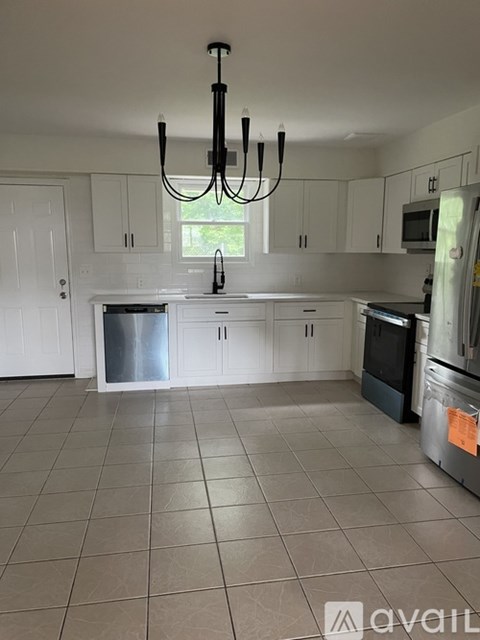 A kitchen with white cabinets and a tiled floor.