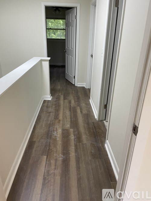 A hallway with wood flooring and white walls.