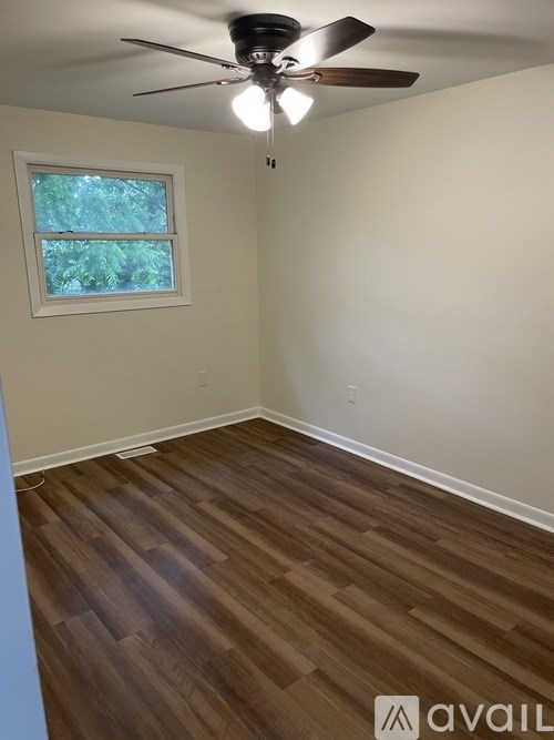 A room with a ceiling fan and wooden flooring.