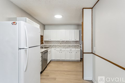 A white refrigerator is in a kitchen with white cabinets.