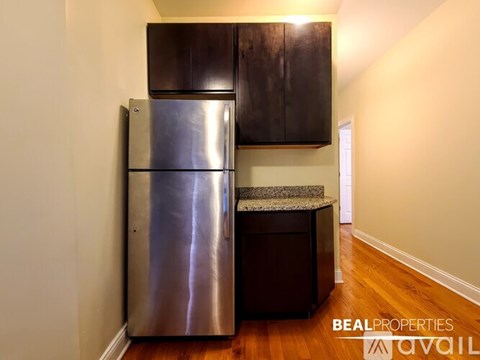 A stainless steel refrigerator in a kitchen with wooden cabinets and a granite countertop.