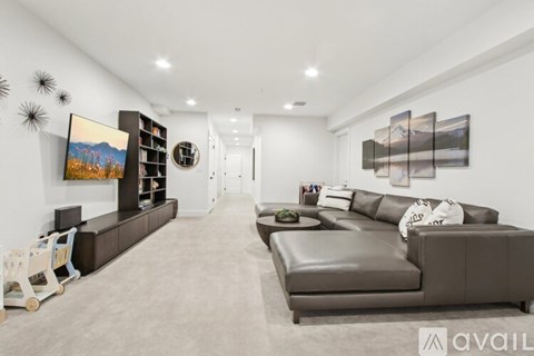 A living room with a grey sofa and a painting on the wall.