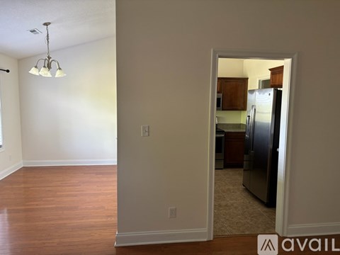 A kitchen is visible through an open door in a living room.