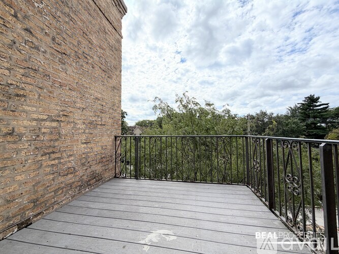 A balcony with a brick wall and metal railing.