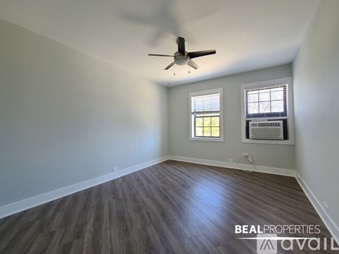 A room with a ceiling fan and two windows.