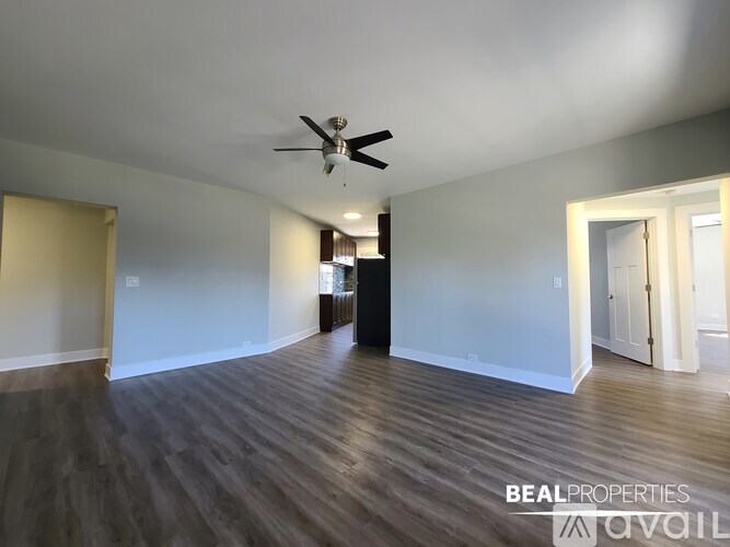 A spacious room with a ceiling fan and wooden flooring.