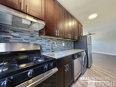 A modern kitchen with dark wood cabinets and stainless steel appliances.