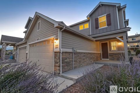 A house with a grey exterior and a brown brick wall is available for sale.