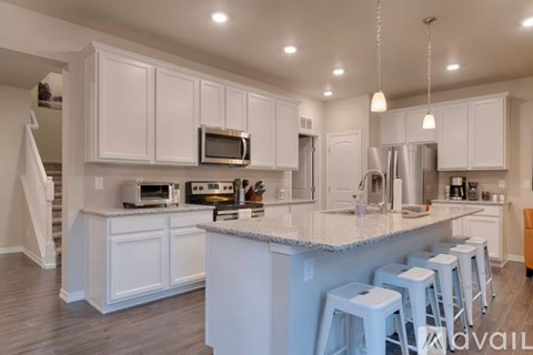 A kitchen with white cabinets and a large island with bar stools.