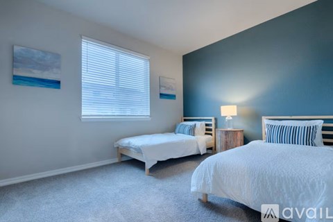 Two twin beds in a bedroom with blue walls and carpet.