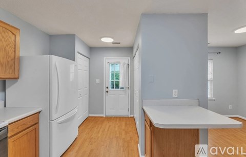 A kitchen with a white refrigerator and wooden cabinets.
