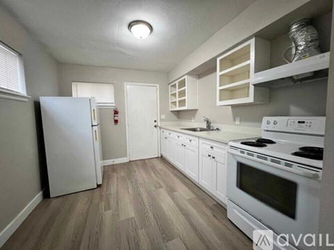A kitchen with white appliances and wooden floors.