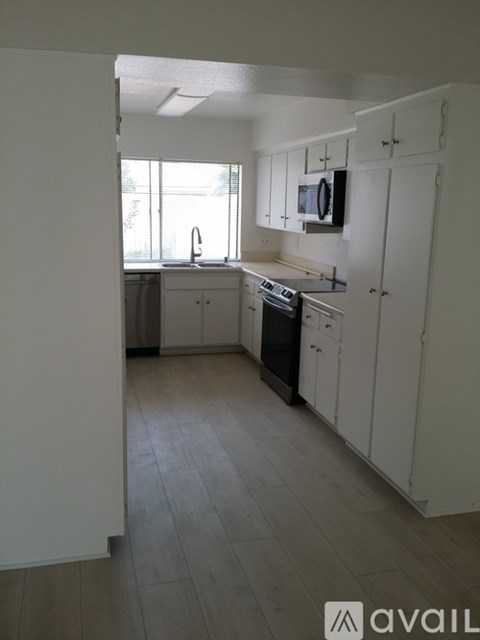 A kitchen with white cabinets and a wooden floor.