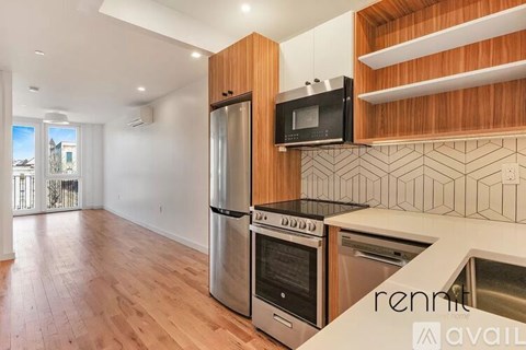 A kitchen with a wooden cabinet and a black microwave.