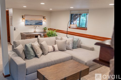 A living room with a grey couch, a wooden coffee table, and a painting on the wall.