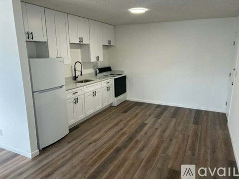 A kitchen with white cabinets and a wooden floor.
