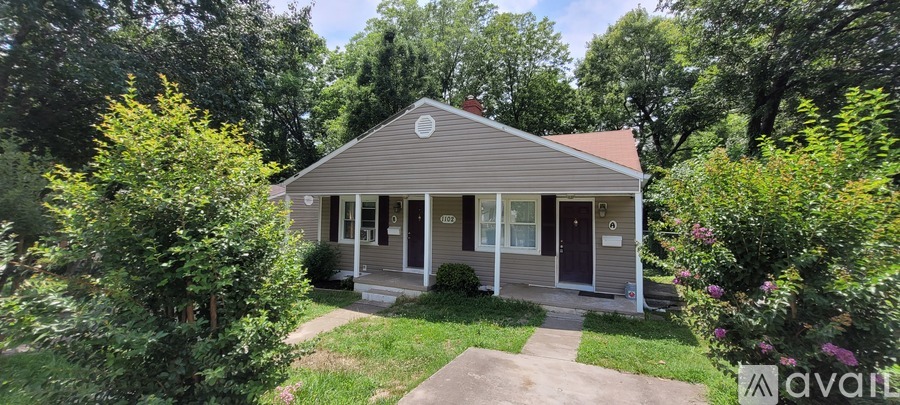 A small house with a front porch is surrounded by greenery and has a sign that says "available".