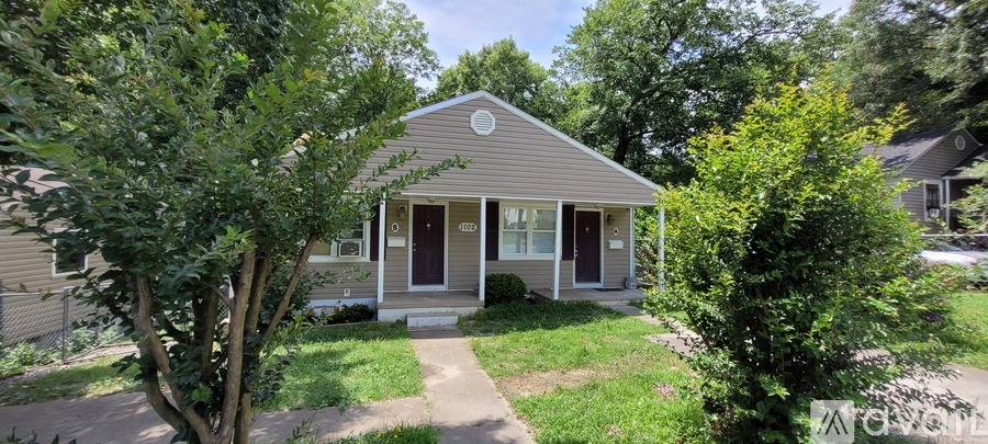 A small house with a brown door and windows surrounded by trees.