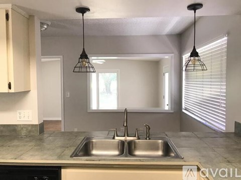 A kitchen with a sink and a window with blinds.