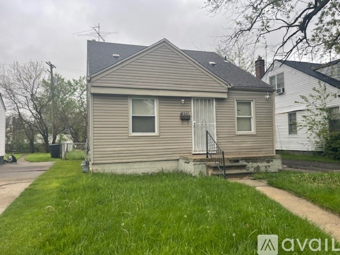 A house with a grey siding and a white door is for sale.
