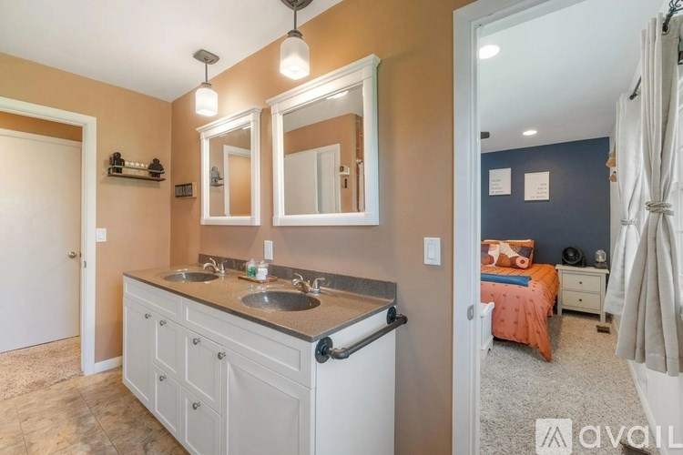 A bathroom with a double sink vanity and a mirror above it.