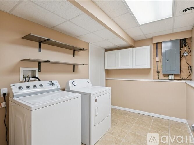 A grassy field with trees and houses in the background.