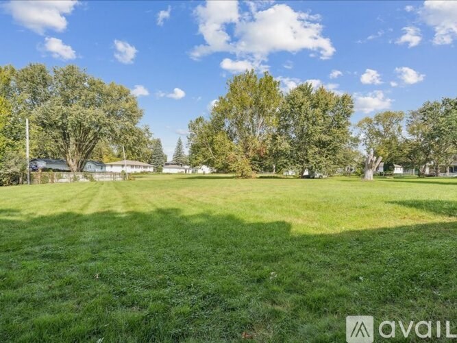 A grassy field with trees and a clear sky.