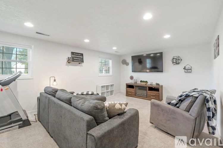 A living room with a grey couch and a television mounted on the wall.