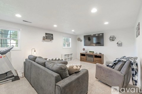 A living room with a grey couch and a television mounted on the wall.