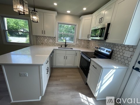 A kitchen with white cabinets and a hanging light fixture.