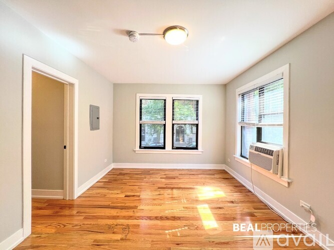 A room with wooden floors and two windows with blinds.