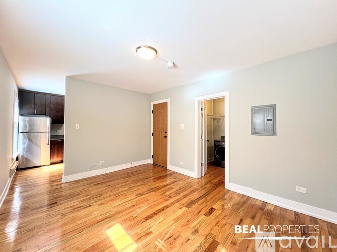 A room with wooden floors and white walls, with a window on the left side.
