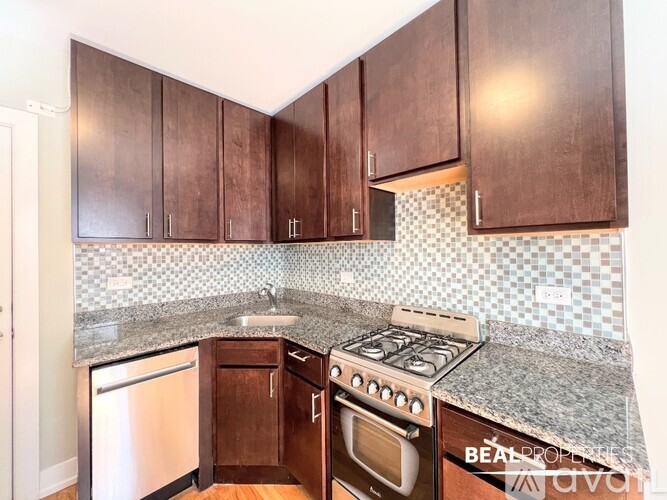 A kitchen with dark brown cabinets and a granite countertop.