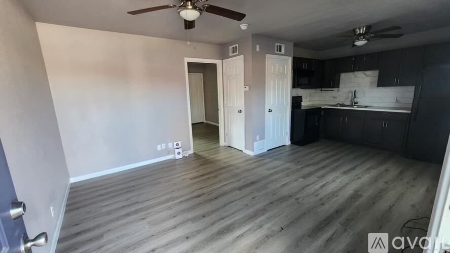 A room with a ceiling fan and a doorway leading to another room.