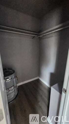 A small, empty room with a trash can and a door on the right.